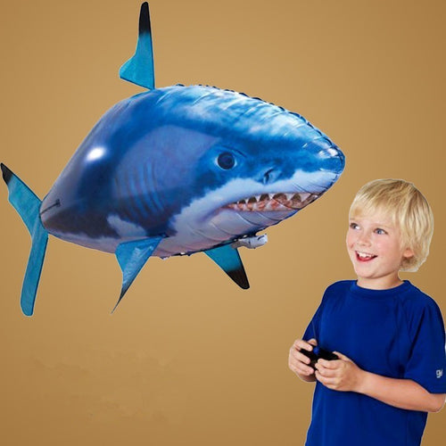 Tap Once remote control flying shark balloon toy being operated by a young boy in a blue shirt